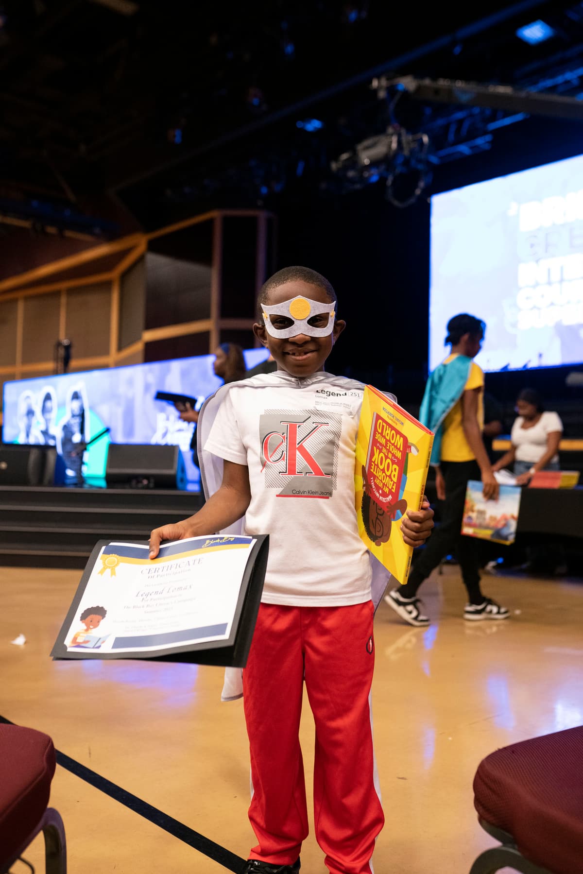 Graduate holding his certificate and book in cape and mask